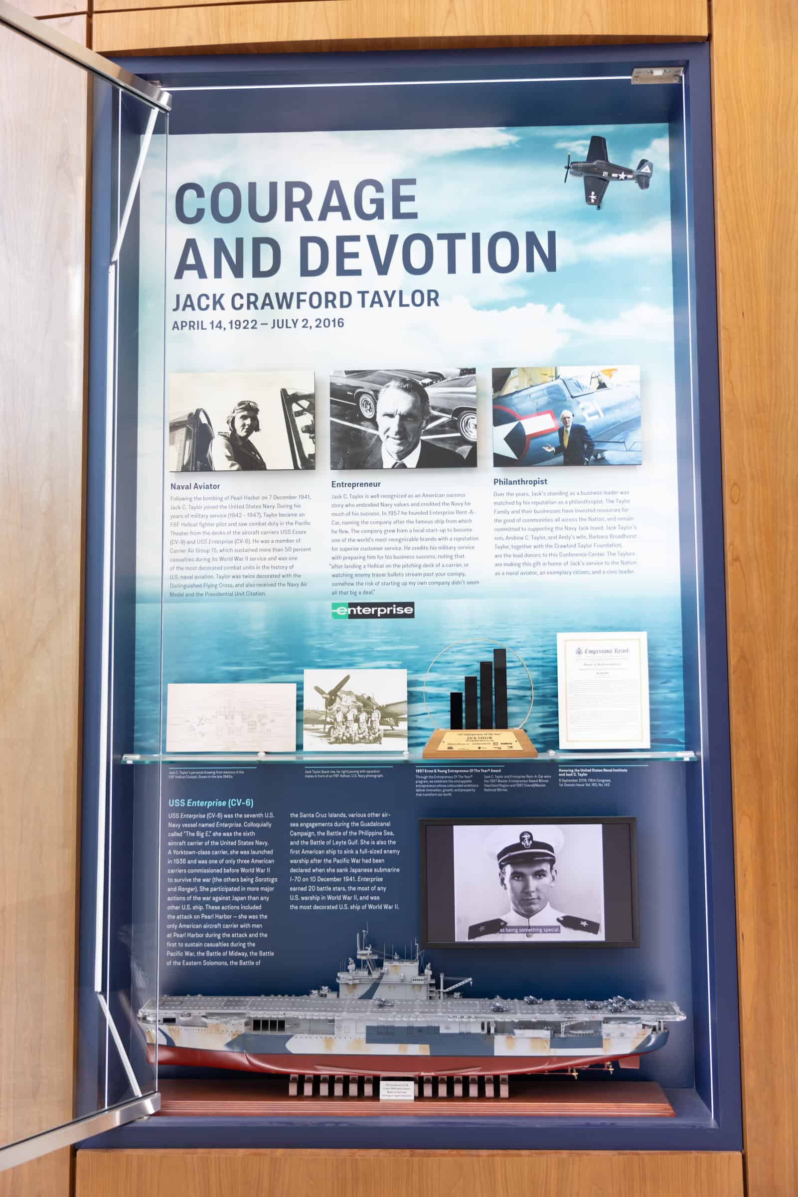 Tribute display for Jack Crawford Taylor: text, images, bar chart, model ship; background of courage with photos and naval ship.